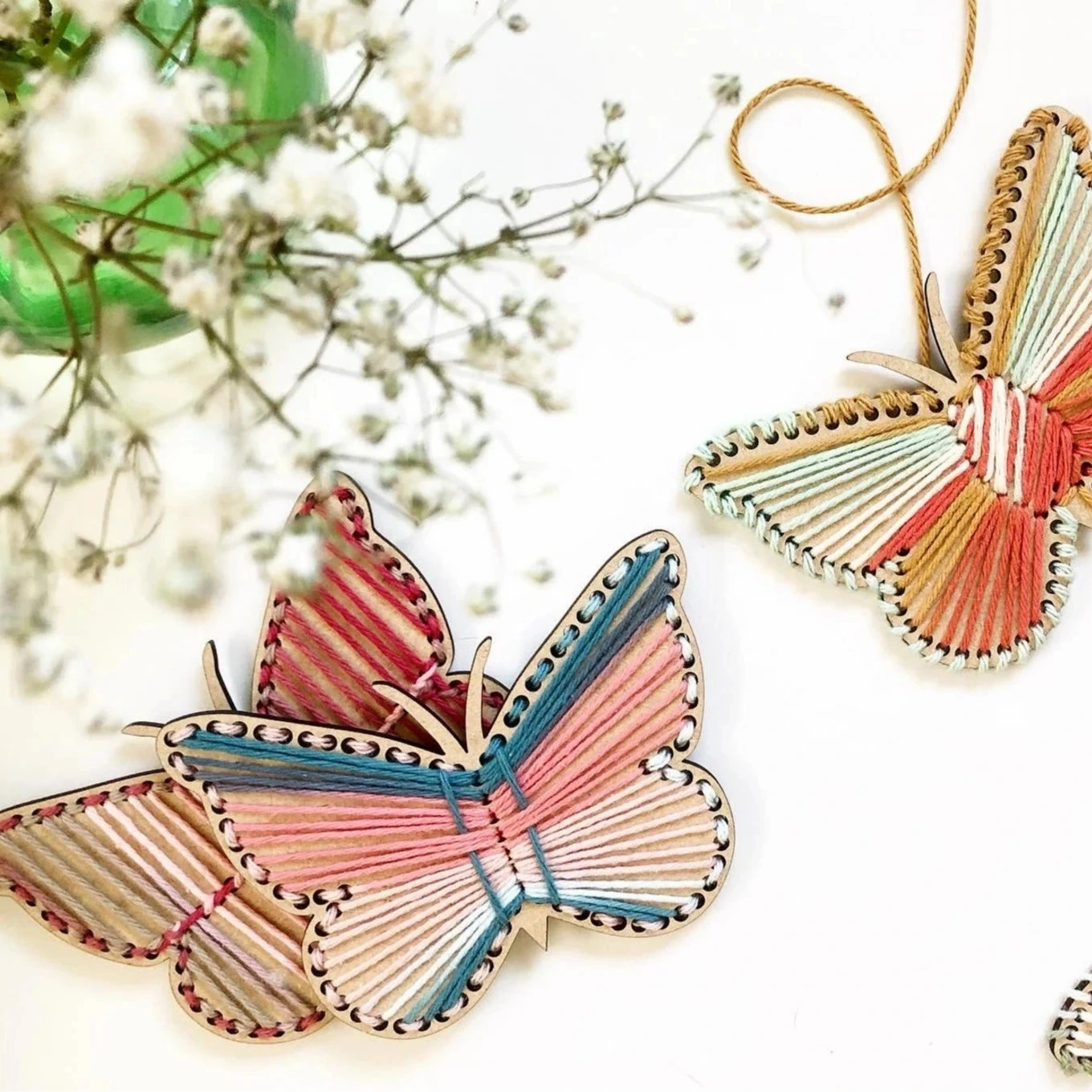 Three colorful butterfly-shaped decorations on a white background with small white flowers.